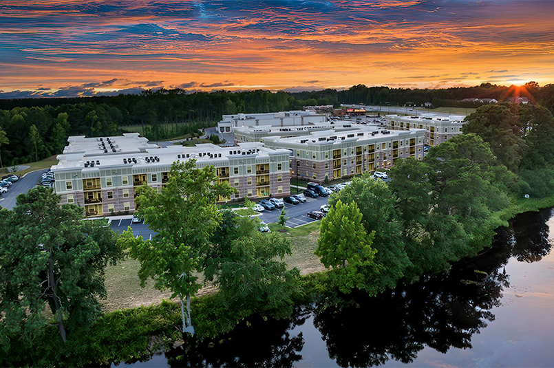 Residential buildings along a pond with a sunset behind